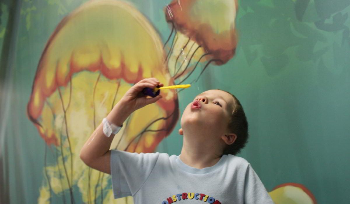 Boy in hospital blowing bubbles,
