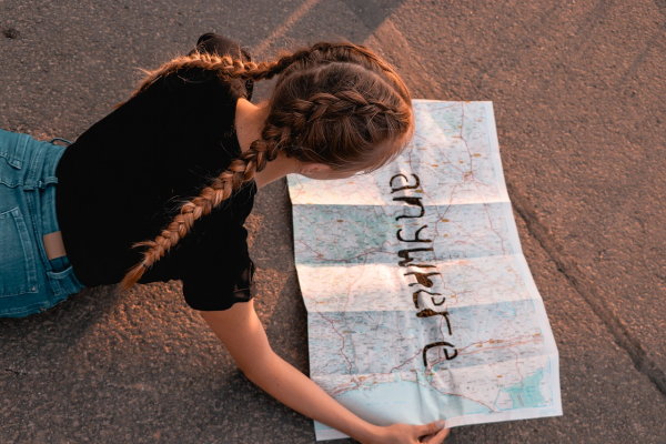 Girl with braids looking at map with the word anywhere cut out