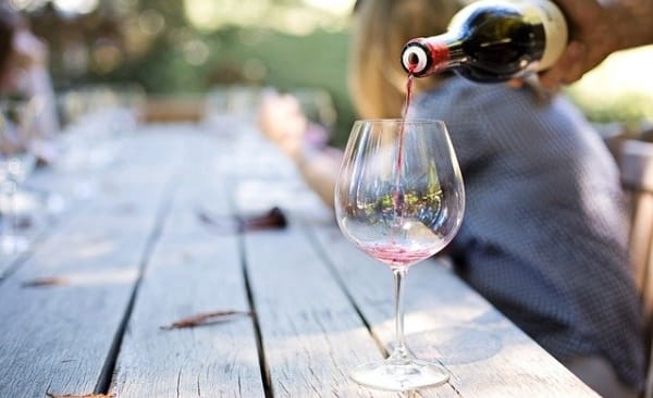 Wine being poured into a glass on an outdoor picnic table