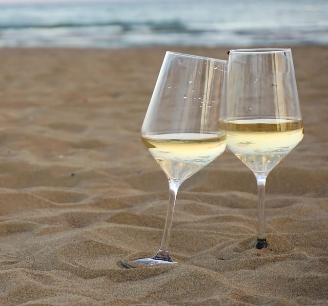 two white wine glasses on the beach